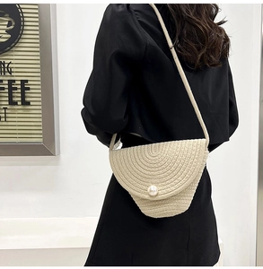 Detail of handmade beige straw bucket bag with large pearl buckle on a shoulder strap