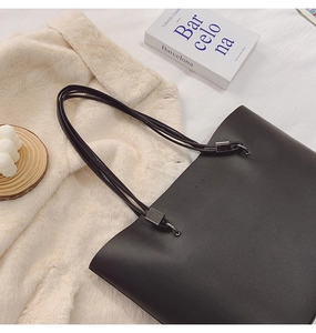 Détail montrant la texture cuir noir mat et le logo Fashion embossé sur le sac fourre-tout