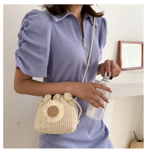 Detail of hand-woven straw bucket bag featuring a 3D sunflower and thin cord shoulder strap