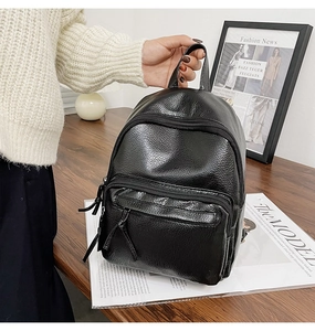 Close-up of a black faux leather backpack with litchi texture on a wooden table