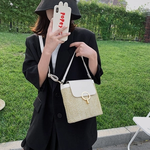 Handwoven beige straw crossbody bag with white leather flap and gold circular buckle