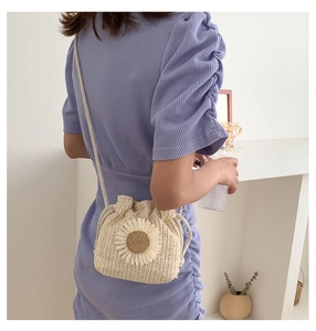 Detailed view of mini woven straw bucket bag featuring 3D sunflower and drawstring closure