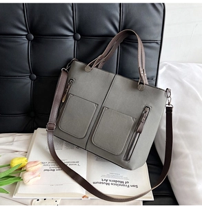 Detail of grey frosted faux leather tote with brown handles and front zip pockets