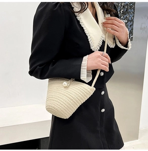 Gros plan du sac seau tissé beige avec perle décorative et fine bandoulière