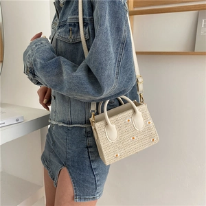 Sac fourre-tout chic en paille beige avec broderie marguerite porté par un modèle