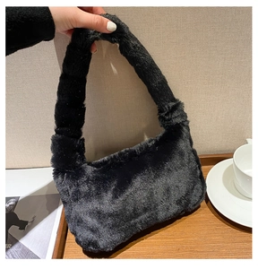 Détail d'un sac à bandoulière en peluche noire avec une poignée épaisse et douce