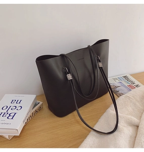 Détail d'un grand sac cabas noir montrant la texture du cuir et les boucles métalliques