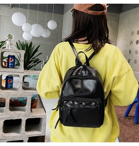 Detail of a black pleated texture backpack worn with a vibrant yellow sweatshirt