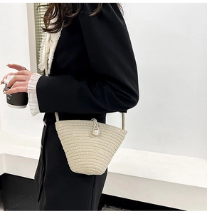 Détail d'un sac seau en paille tressée avec fermoir perle et texture raffinée
