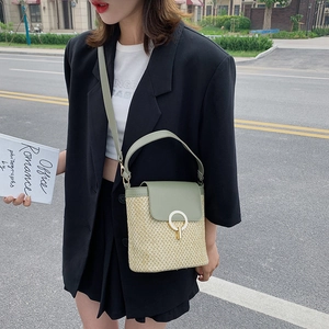 Chic straw bucket bag with green leather trim and round metal buckle for summer vacations