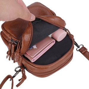 Brown litchi leather crossbody bag with multiple zippers showing interior storage space