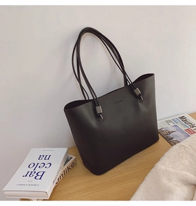 Détail d'un sac cabas en cuir mat noir minimaliste avec logo FASHION sur bois