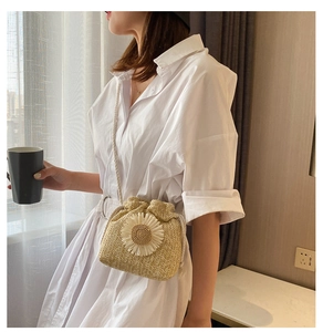 Detail of a straw bucket bag with a large white 3D sunflower and drawstring closure