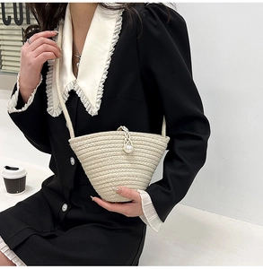 Détail d'un sac seau en paille beige tissé main avec un grand fermoir perle élégant
