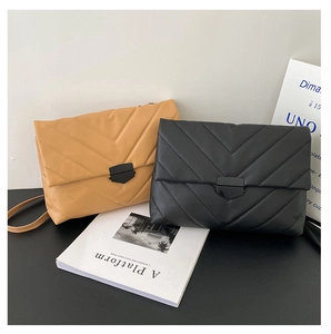 Detail of V-quilted faux leather envelope bags with black metal clasps in black and mustard
