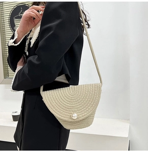 Handmade cream woven crossbody bucket bag with pearl closure and sleek shoulder strap