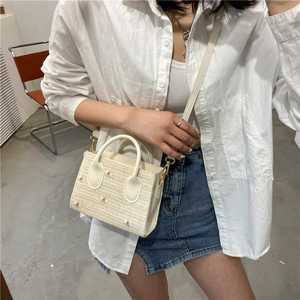 Sac fourre-tout tressé blanc avec broderie marguerite, porté en bandoulière d'été
