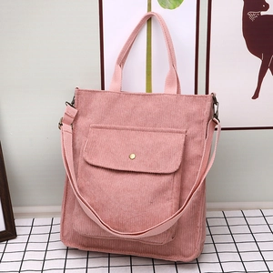 Pink corduroy tote bag with front flap pocket and adjustable strap in minimalist setting
