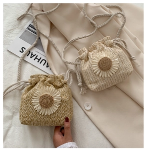 Detailed view of woven bucket bag with large 3D daisy flower and thick rope strap