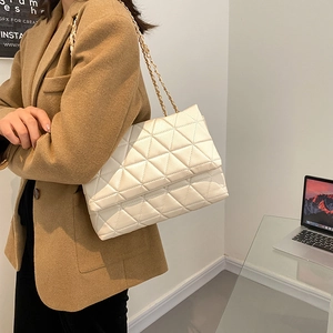 Sac bandoulière blanc matelassé en cuir PU avec chaîne dorée porté par un mannequin chic