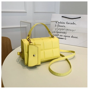 Dettaglio della borsa shopper gialla trapuntata con mini pochette su elegante base bianca