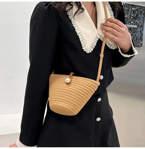 Sac seau en paille avec fermoir grosse perle porté par un mannequin au style naturel