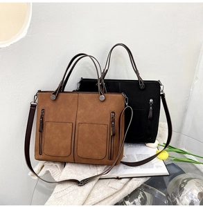 Close-up of matte suede tote bags in brown and black with dual front zipper pockets