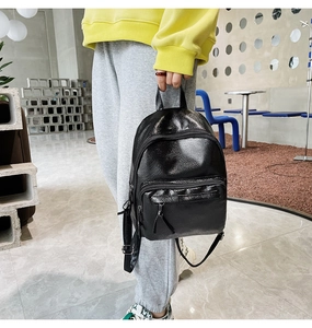 Detail of black pebbled faux leather backpack featuring multiple pockets and adjustable straps