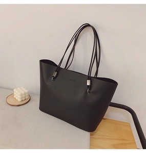 Détail d'un grand sac cabas noir avec lettrage FASHION sur un matériau en cuir mat