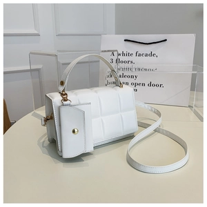 Dettaglio di una borsa bianca trapuntata con finiture dorate e mini pochette rimovibile