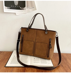 Detail of dark brown matte leather tote bag with functional double pockets and side zippers
