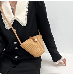 Détail du sac seau en paille avec fermoir grosse perle et bandoulière tissée ajustable