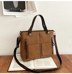 Retro brown faux suede handbag with dual front pockets and silver hardware on wooden surface