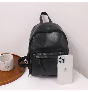 Detail of black pebbled faux leather backpack with double tassel zipper and phone for scale
