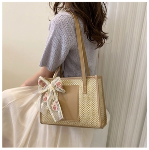 Détail d'un sac cabas tissé avec nœud en dentelle florale et écusson en cuir marron