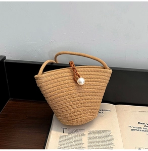 Détail d'un sac seau tissé à la main avec perle décorative et poignée en cordon brun