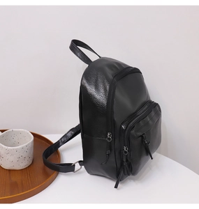 Detail view of black lychee-textured PU leather mini backpack with side pocket and zipper