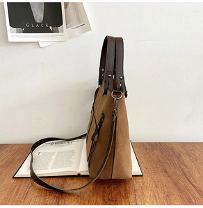 Detail of brown frosted leather tote bag with decorative side zipper and metal rivets