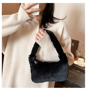 Détail d'un sac à main en peluche noire avec fermeture éclair dorée dans un café