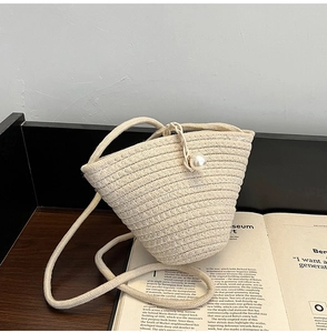 Détail d'un sac seau tressé crème avec fermoir perle et texture de corde tissée