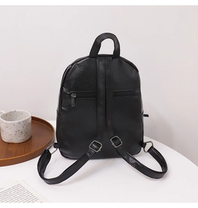 Rear view of black backpack with adjustable straps and hidden pocket on white table