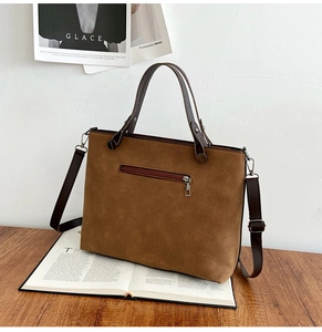 Detailed view of a brown suede tote bag with dual front zipper pockets and leather handles