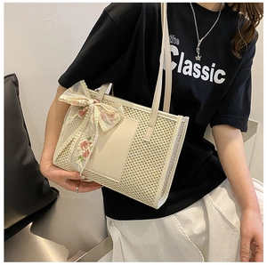 Détail du sac cabas en paille avec un nœud en dentelle beige et une broderie florale
