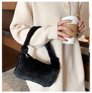 Détail du sac baguette en fausse fourrure noire avec texture douce et zip doré