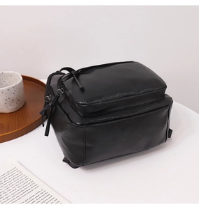 Detail of black pebbled leather backpack showing multi-layered zipper compartments