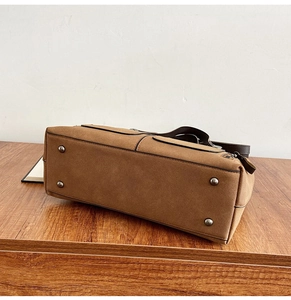 Detail view of the brown nubuck handbag base featuring four protective silver metal feet