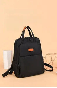 Detail of black nylon laptop backpack featuring vibrant orange leather accents and zips