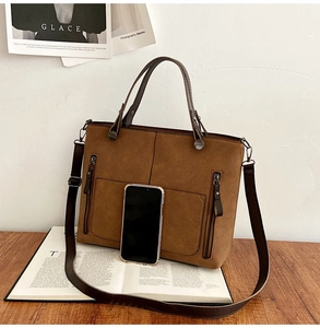 Detail of vintage brown frosted leather tote bag with sturdy handles and side zippers