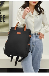 Detail aus wasserdichtem Oxford-Gewebe und braunen Lederakzenten am schwarzen Laptop-Rucksack