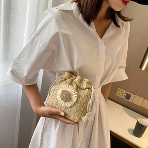 Woven straw bucket bag with white daisy flower and drawstring strap in a soft summer style